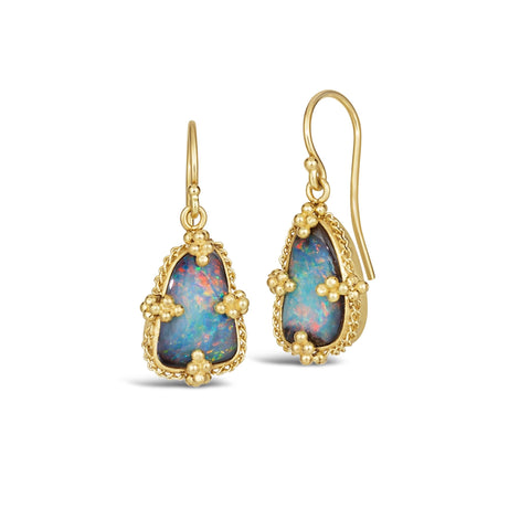 A pair of small blue Boulder opal earrings that are set in 18k yellow gold chain wrapped bezels and hang on French hook closures.