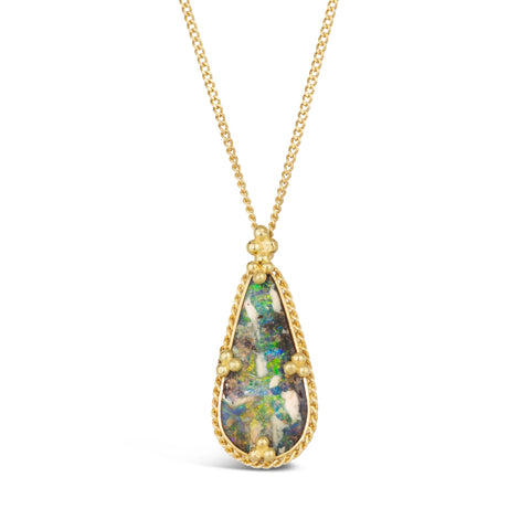 A teardrop shaped opal is set in an 18k yellow gold bezel surrounded by chain and four beaded prongs on a delicate chain