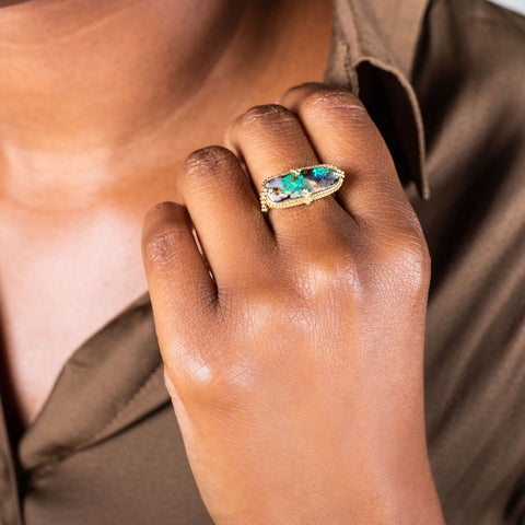 A model wears a large rectangular opal ring set in 18k yellow gold