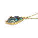A side view of an andamooka opal, with blue and black hues, that has a skull carved into the stone. The pendant is set in an 18k yellow gold chain wrapped bezel with four beaded prongs and hangs on a delicate short chain.