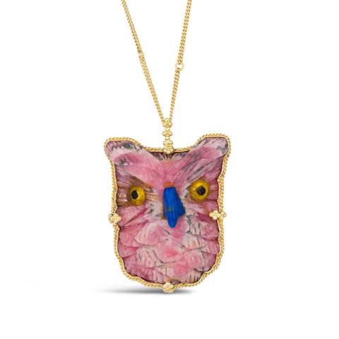 A light pink rhodochrosite is carved into an owl with gold and black eyes and a blue beak. The stone is wrapped in an 18k yellow gold braided bezel with four beaded prongs around the edge and hangs from a delicate chain.