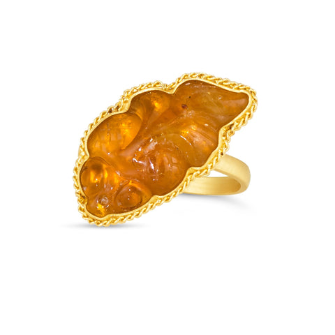 This orange hued tourmaline ring is carved into the shape of a fish that is set in an 18k yellow gold chain wrapped bezel. The stone sits on a thin band.