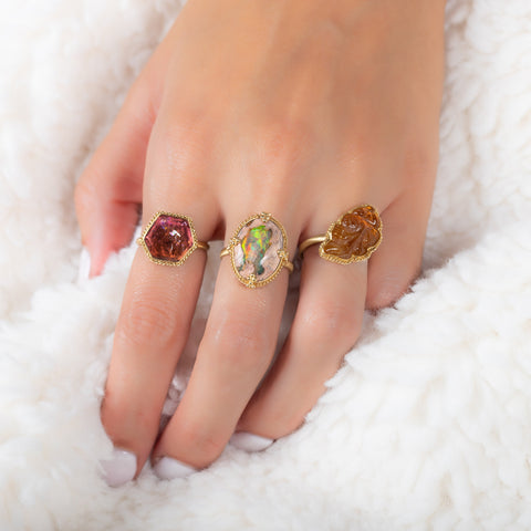 A model wears three rings, including a fish carved tourmaline ring, a Mexican opal ring and a hexagon shaped tourmaline ring.