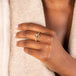 A model wears a rectangular faceted champagne diamond ring with a chain wrapped 18k yellow gold bezel and four prongs on a thin band