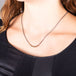 A model wears a short necklace with a row of 18k yellow gold wrapped black diamonds on an oxidized sterling silver chain.