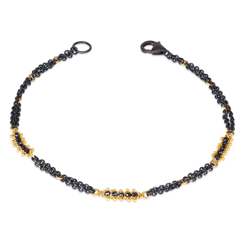 This oxidized sterling silver chain bracelet has three black diamond and 18k yellow gold bars stationed throughout.