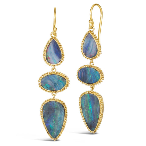This pair of boulder opal earrings feature three stones wrapped in 18k yellow gold chain wrapped bezels. The stones hang from a French hook closure. 