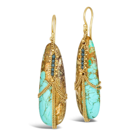 A pair of large turquoise earrings hang from french hook closures that feature blue diamonds wrapped in chain.