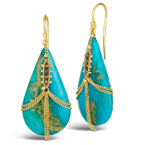This pair of teardrop shaped turquoise earrings are draped in 18k yellow gold chain and champagne diamonds. The stones hang from French hook closures. 