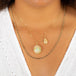 A model wears a large oval shaped Ethiopian opal pendant, set in an 18k yellow gold chain wrapped bezel.