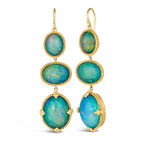 A pair of long earrings are crafted with three oval shaped Ethiopian opal stones, which are set in chain wrapped 18k yellow gold bezels and joined together dangling from French hooks.