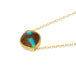 A side view of an eye shaped opalized wood stone pendant, with a streak of blue in the middle of a dark brown wood, is set in an 18k yellow gold bezel. The stone is suspended horizontally on a delicate chain.