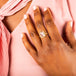 A model wears a medium sized faceted morganite ring set in a chain wrapped bezel with four beaded prongs on a thin band.