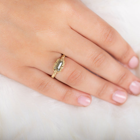 A model wears a small rectangular diamond ring set in an 18k yellow gold chain wrapped bezel with four beaded prongs.