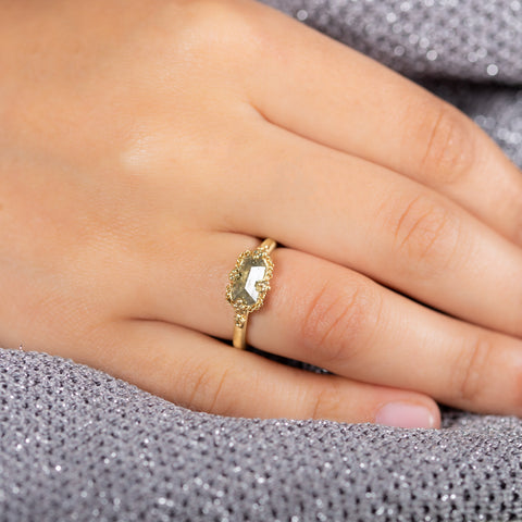A model wears a small rectangular diamond ring set in an 18k yellow gold chain wrapped bezel with four beaded prongs.