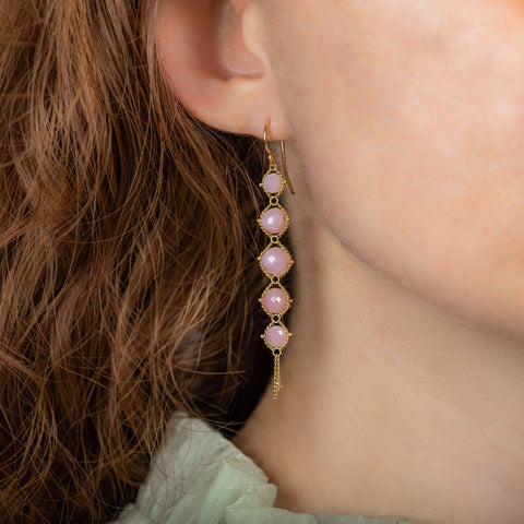 A model wears a long graduated pink opal earring suspended in 18k yellow gold chain.