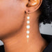 A model wears a long graduated pearl earring suspended in 18k yellow gold chain.