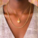 A model wears two layered necklaces, one featuring a Mexican opal pendant, and the other with graduated tourmaline stones.