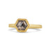 A small hexagon shaped charcoal colored diamond is set in a chain wrapped 18k yellow gold bezel on a thin ring band.