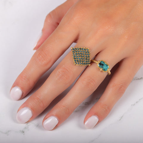 A model wears two rings, including a small Peruvian opal ring and a woven blue diamond textile ring.