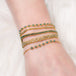A model wears a stack of five delicate 18k yellow gold chain bracelets.