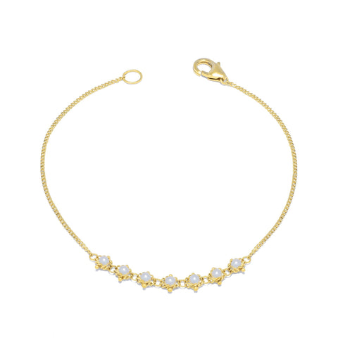 This delicate 18k yellow gold chain bracelet features a row of woven pearls in the center and closes with a lobster clasp.