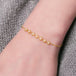 This delicate 18k yellow gold chain bracelet features a row of woven pearls in the center and closes with a lobster clasp.