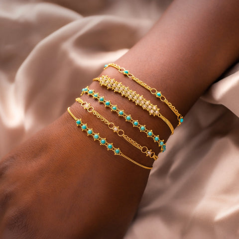 A model wears a stack of five 18k yellow gold and turquoise bracelets.