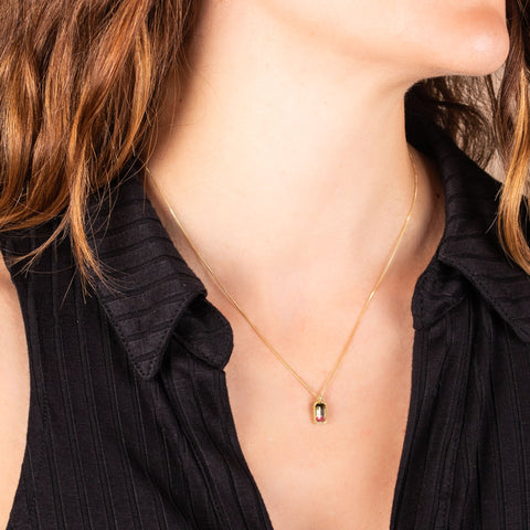 A model wears a small rectangular faceted watermelon tourmaline pendant set in an 18k yellow gold chain wrapped bezel on a short delicate chain.