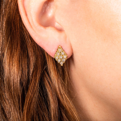 A model wears an earring crafted in 18k yellow gold chain and grey diamonds that are woven into a diamond lattice pattern and fastened with a post closure.