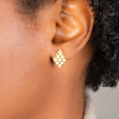 A model wears an earring crafted in 18k yellow gold chain and white pearls that are woven into a diamond lattice pattern and fastened with a post closure.