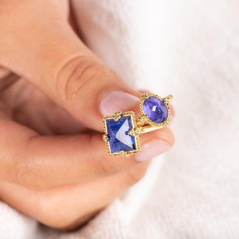 A model holds two 18k yellow gold and Tanzanite rings.