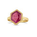 A faceted hexagon shaped ruby is set in an 18k yellow gold bezel with a braided detail around the edge on a thin ring band.