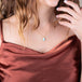 A model wears a short necklace featuring a teardrop shaped turquoise pendant set in 18k yellow gold with a braided detail and granulated prongs.