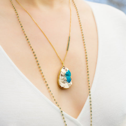 This Cavansite crystal necklace is set in an 18k yellow gold bezel and hangs from a chain that features a row of woven blue diamonds.