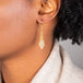 A model wears an earring crafted in 18k yellow gold chain and silver diamonds that are woven into a diamond lattice pattern.