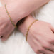 A model wears a woven 18k yellow gold and diamond bracelet on each hand.