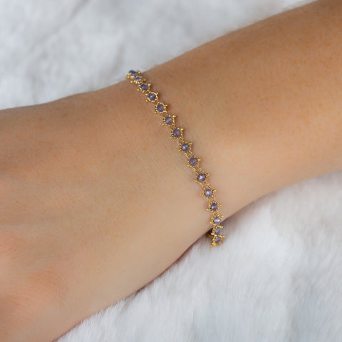 This 18k yellow gold bracelet features tanzanite beads woven throughout a delicate chain. The bracelet features a lobster clasp closure.