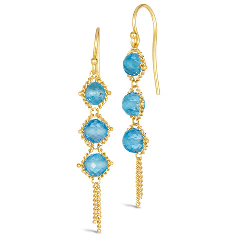 A pair of long 18k yellow gold earrings are crafted with blue topaz beads suspended in delicate chain. The earrings are fastened with French hook closures.