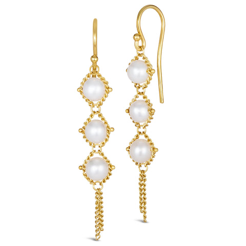 A pair of long 18k yellow gold earrings are crafted with white pearl beads suspended in delicate chain. The earrings are fastened with French hook closures.