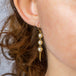 A model wears a white pearl trio earring suspended in 18k yellow gold chain.
