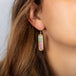 A pair of long rectangular tourmaline earrings, featuring pale pink and green hues. The stones are set in 18k yellow gold chain wrapped bezels with two beaded prongs. The earrings hang on French hook closures.