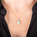 A small teardrop shaped turquoise pendant is set in 18k yellow gold and hangs on a short chain.