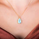 A teardrop shaped turquoise stone is set in 18k yellow gold and hangs on a delicate chain.