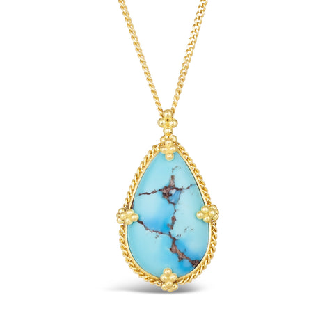 A teardrop shaped turquoise stone with brown veins is set in an 18k yellow gold bezel with braided details and granulated prongs. The pendant hangs on a thin gold chain.