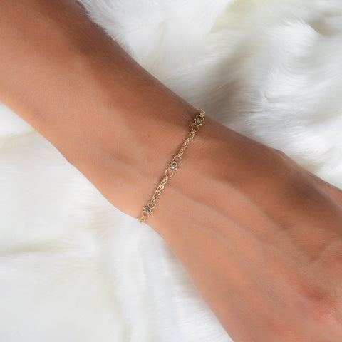 This delicate 18k yellow gold chain bracelet is dotted with grey diamond beads throughout. The bracelet is finished with a lobster clasp closure.