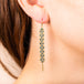 A model wears a long 18k yellow gold woven chain earring with blue diamond beads throughout.